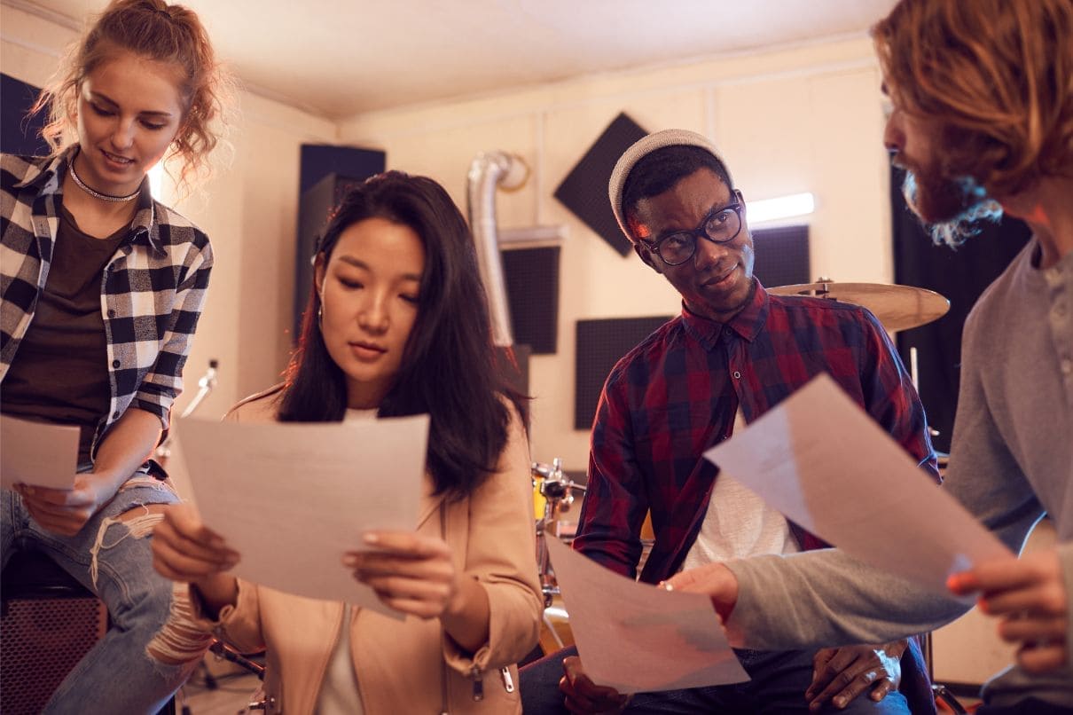 A diverse group of individuals in a recording studio, attentively examining papers and collaborating.